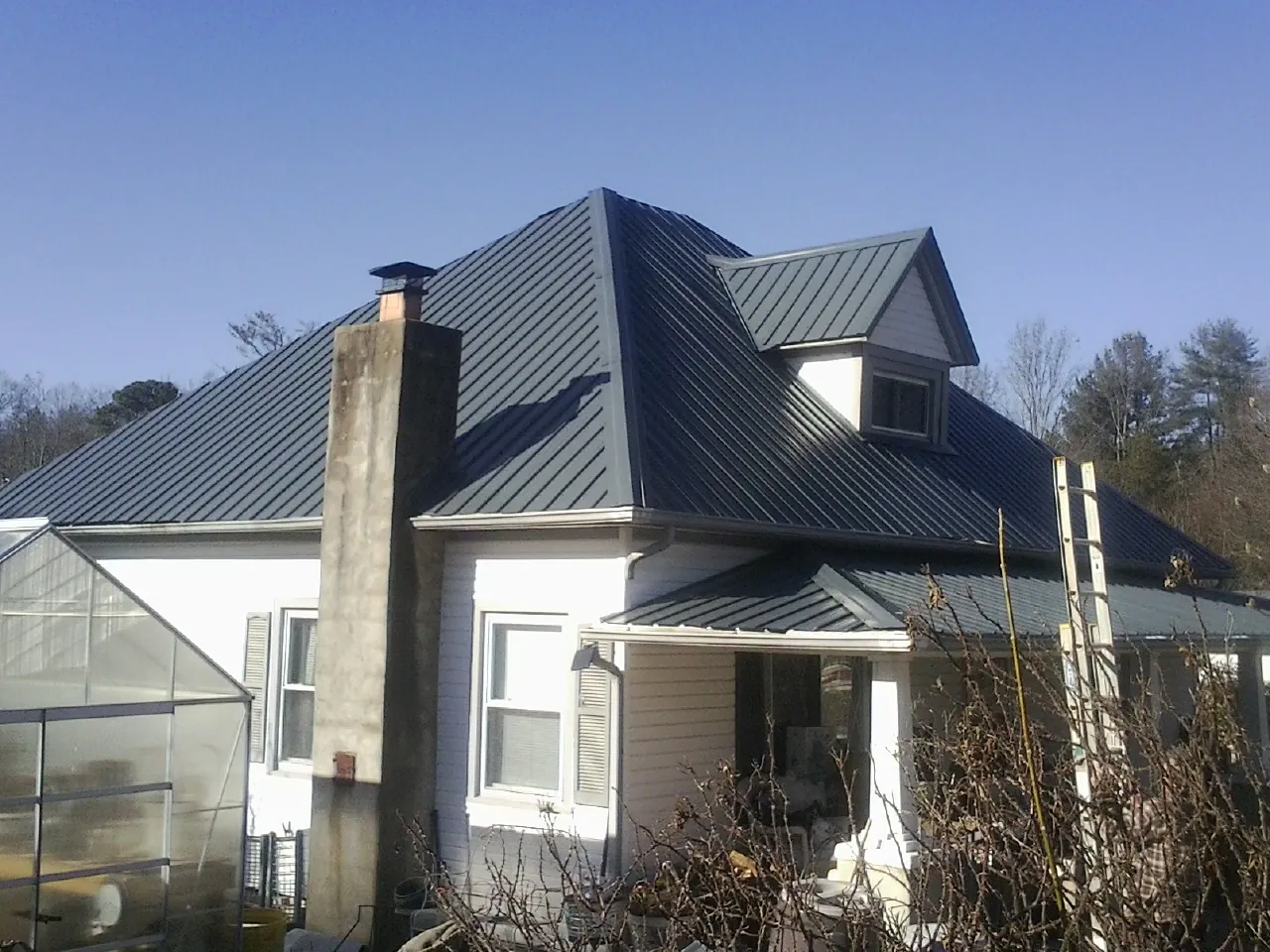Dark blue standing seam metal roof on a white farmhouse with dormer — Slate & Tile Roof Repair by Roofing Brothers in El Dorado Hills