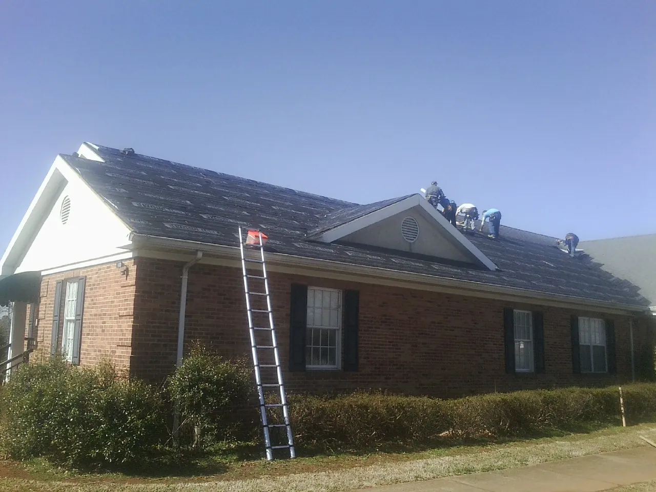 Crew tearing shingles off a brick ranch roof with a ladder set — Metal Roof Repair work by our crew in El Dorado Hills