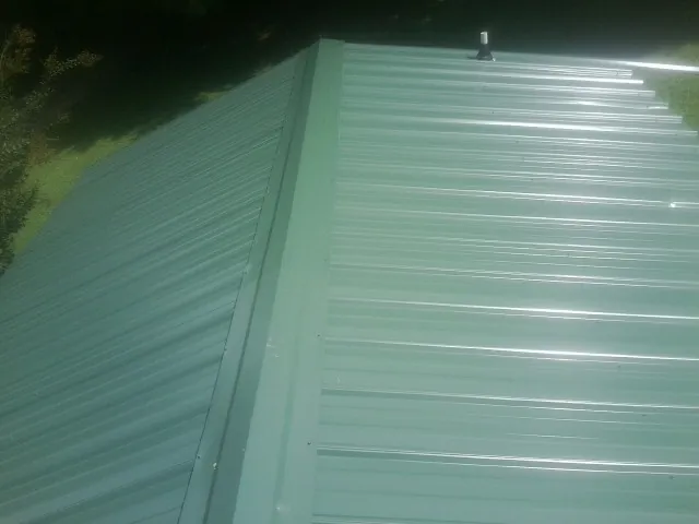 New green metal panels meeting at the ridge of a roof — Flat Roof Repair work by our crew in El Dorado Hills