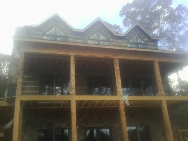 Dormers and porch framing on a large log home under construction — Roof Coating work by our crew in El Dorado Hills