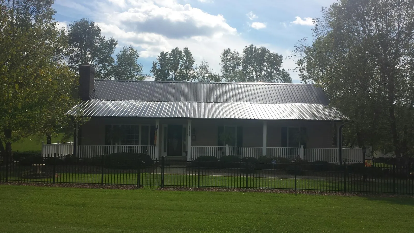 Gray metal roof on a brick ranch with a full width front porch — Gutter Guard Installation work by our crew in El Dorado Hills