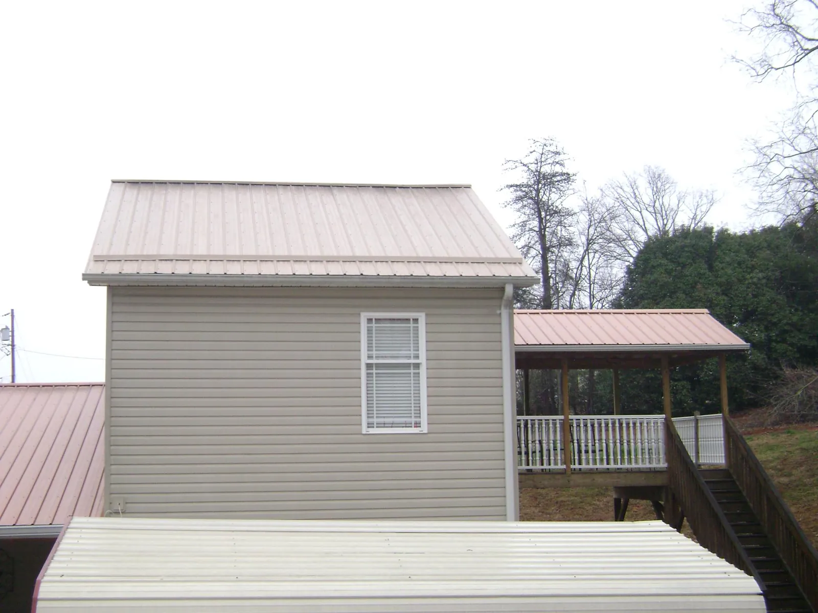 Tan metal roofs on a two story addition and attached porch, from a Roof Replacement job in El Dorado Hills