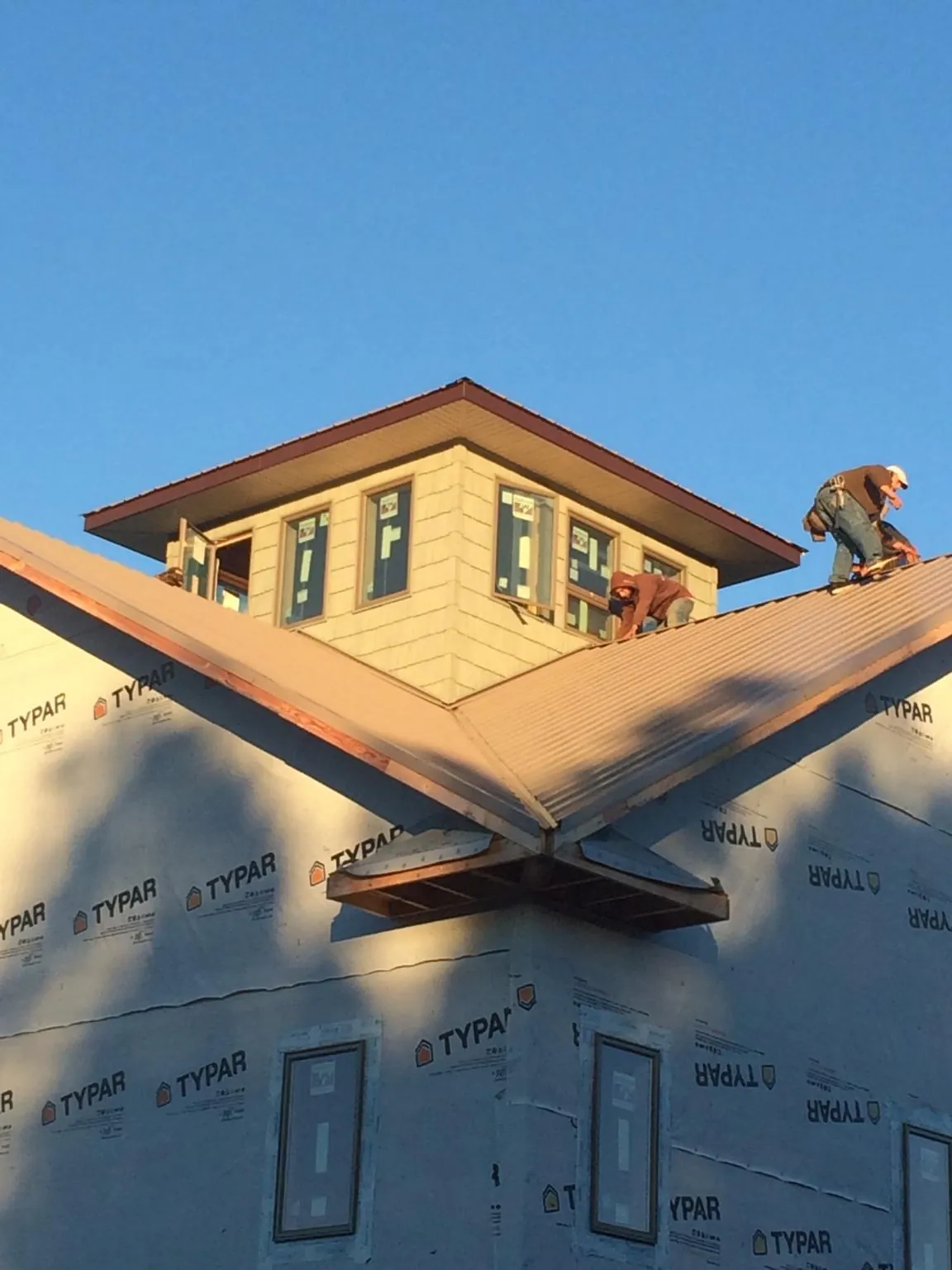 Roofers working around a rooftop cupola on a new metal roof at sunset — Roof Waterproofing in El Dorado Hills by Roofing Brothers